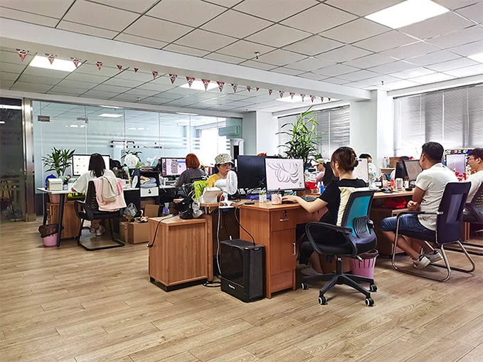 A wide-angle view of a modern open-plan office workspace featuring multiple rows of wooden desks, computer monitors.