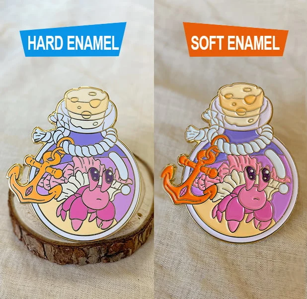 A side-by-side comparison of a custom enamel pin featuring a hermit crab inside a bottle, showcasing a smooth, polished hard enamel finish on the left and a textured, recessed soft enamel finish on the right.