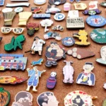 A massive collection of colorful custom enamel pins pinned on a cork board display