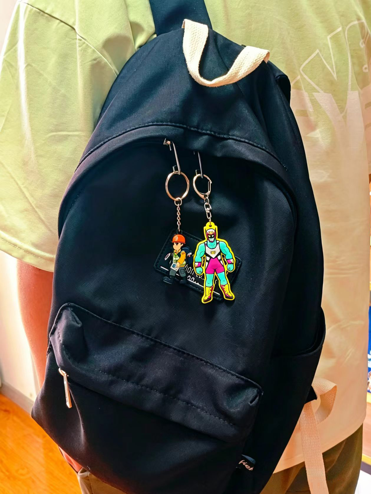 Custom PVC keychains hanging on a black backpack as a trendy lifestyle accessory made by SYD Pins