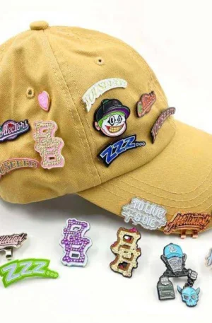 Custom Enamel Hat Pins and Hat Clips - Assortment of Decorative Lapel Pins and Magnetic Hat Clips Displayed on a Khaki Baseball Cap