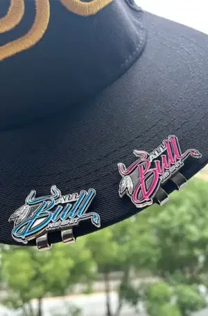 Custom Enamel Hat Clip - Blue and Pink "All Bull No Shit" Magnetic Hat Clips Attached to the Brim of a Black Baseball Cap