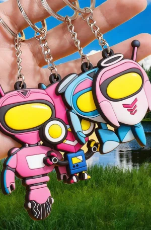 Hand holding a set of custom PVC keychains featuring colorful soft rubber robot and astronaut designs with yellow visors, link chains, and split keyrings against an outdoor scenic background.