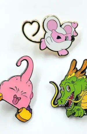 Custom enamel pin set featuring three cute anime and cartoon character designs including a pink creature, green dragon, and heart-tailed mouse with metallic finish