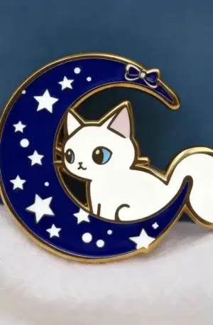 Custom enamel pin featuring a cute white cat sitting inside a deep blue crescent moon with stars and a bow detail with gold plating