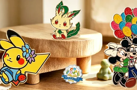 A collection of various custom enamel pins on a wooden display. The image includes an enamel pin of Pikachu with a flower, a Leafeon-inspired enamel pin, a Mickey and Minnie Mouse enamel pin with glitter balloons, and a logo enamel pin with a book and ribbon.